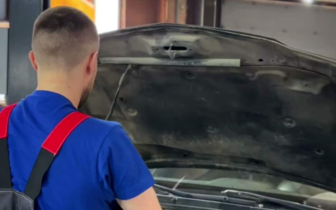 Механик проверяет автомобиль с открытым капотом