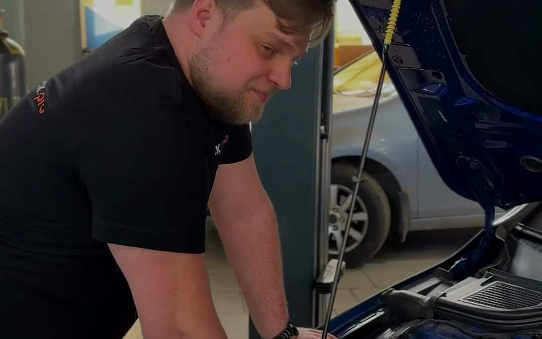 Мастер работает с автомобилем у открытого капота